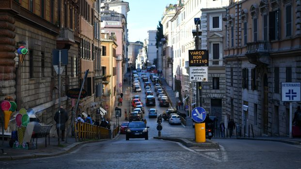 Street scene in Rome with cars and historical buildings, showcasing urban life and architecture.