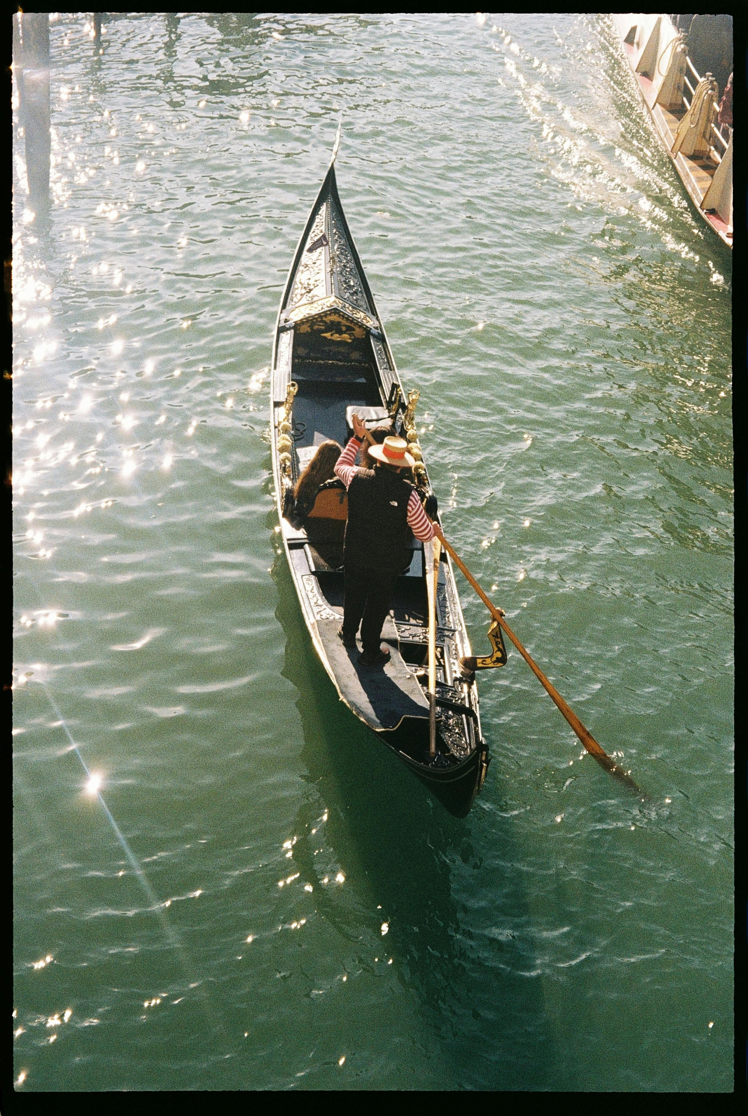 gratis Schilderachtig uitzicht op een gondel die door een kanaal in Venetië vaart, badend in het warme zonlicht. Stockfoto