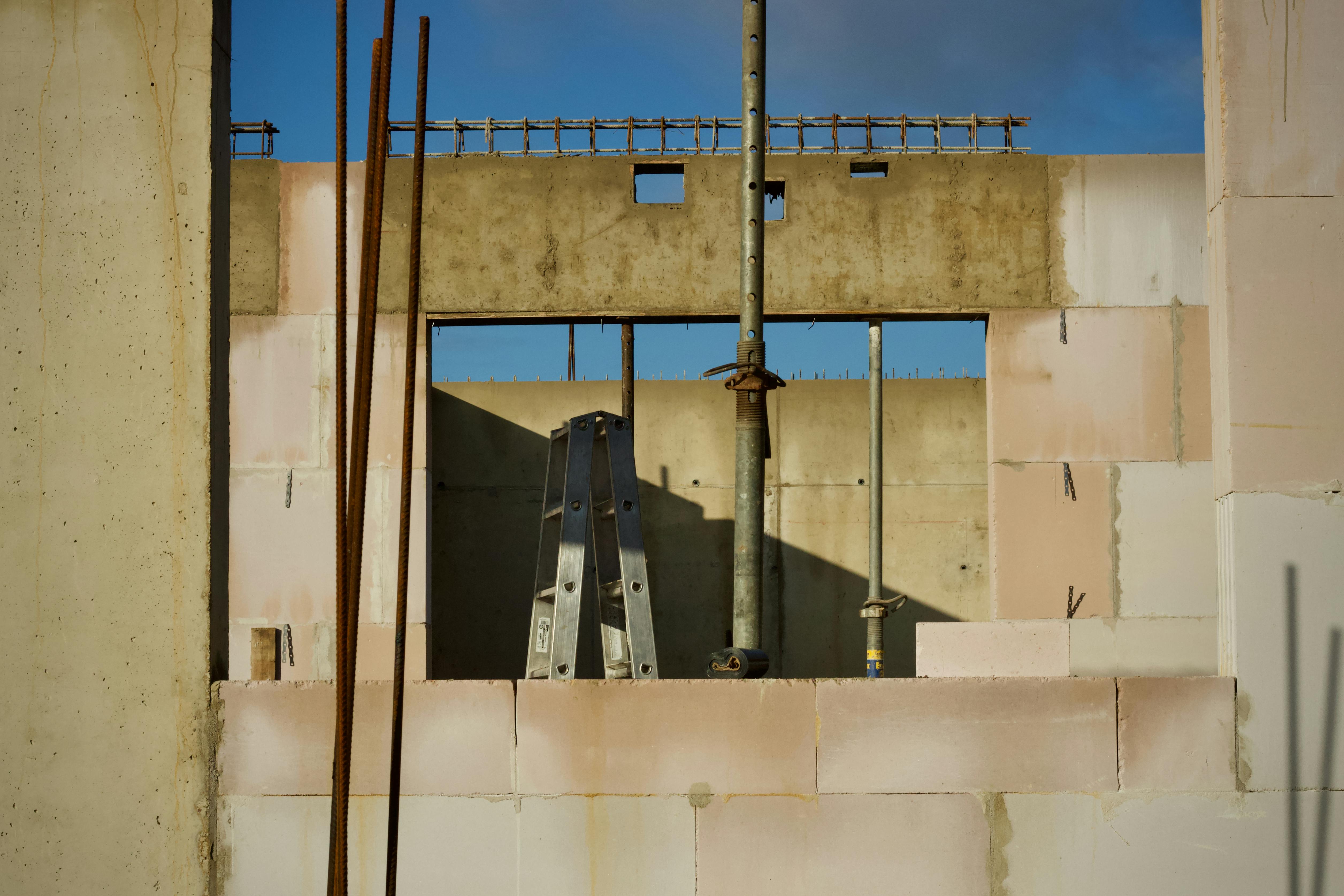 Kostnadsfria Vy över en byggarbetsplats med betongväggar och metallstege under en blå himmel. Stock foto