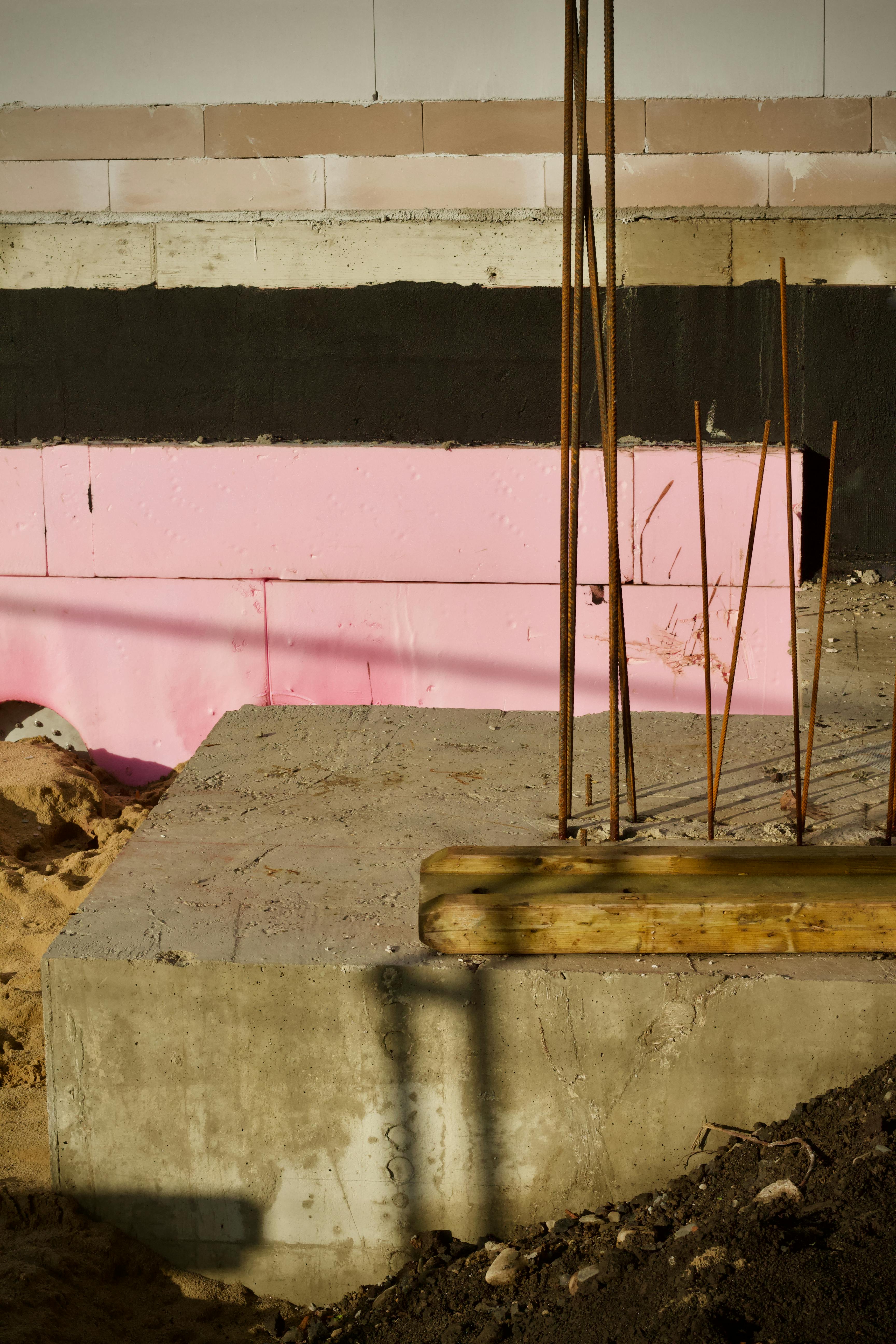 Ücretsiz Pembe ve siyah bir arka plan üzerinde beton ve demir çubukların görüldüğü bir inşaat alanının yakın çekim görüntüsü. Stok Fotoğraflar