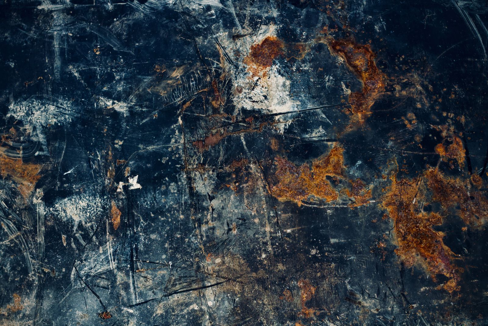 Close-up of a weathered metal surface with blue-grey scratches and copper patina — photo by Peter Dyllong on Pexels