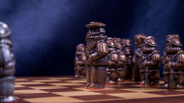 Close-up of a vintage chess set with intricately designed bronze pieces on a wooden board.
