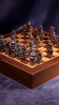Detailed shot of a medieval-style chess set with bronze pieces on a wooden board.