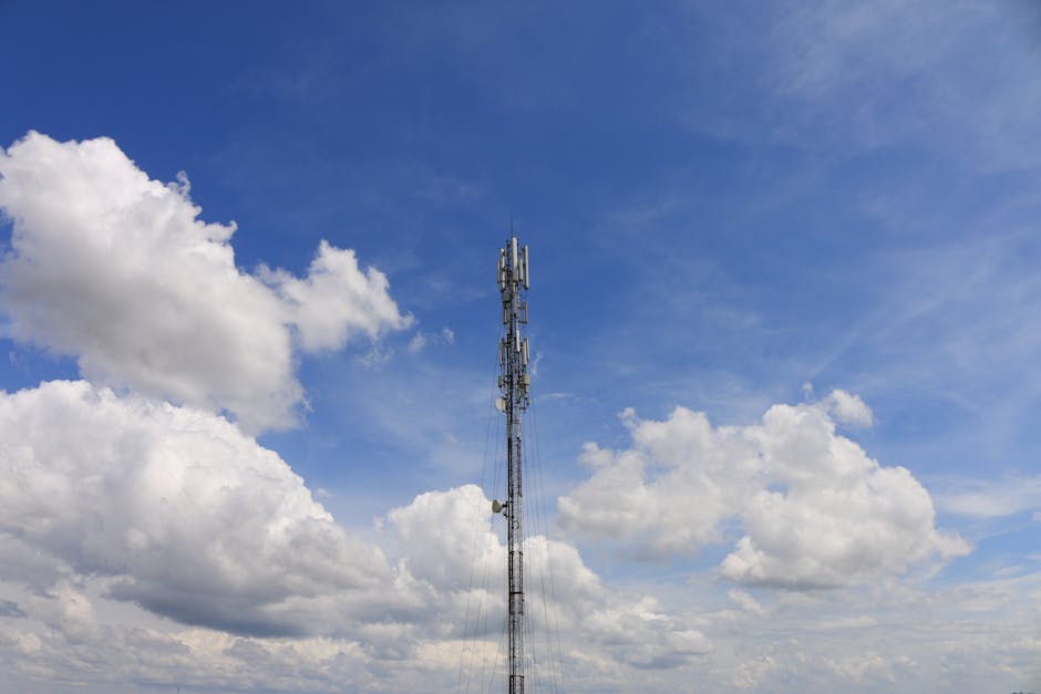 Communication tower standing against a bright, blue sky with fluffy white clouds, suggesting connectivity and technology.