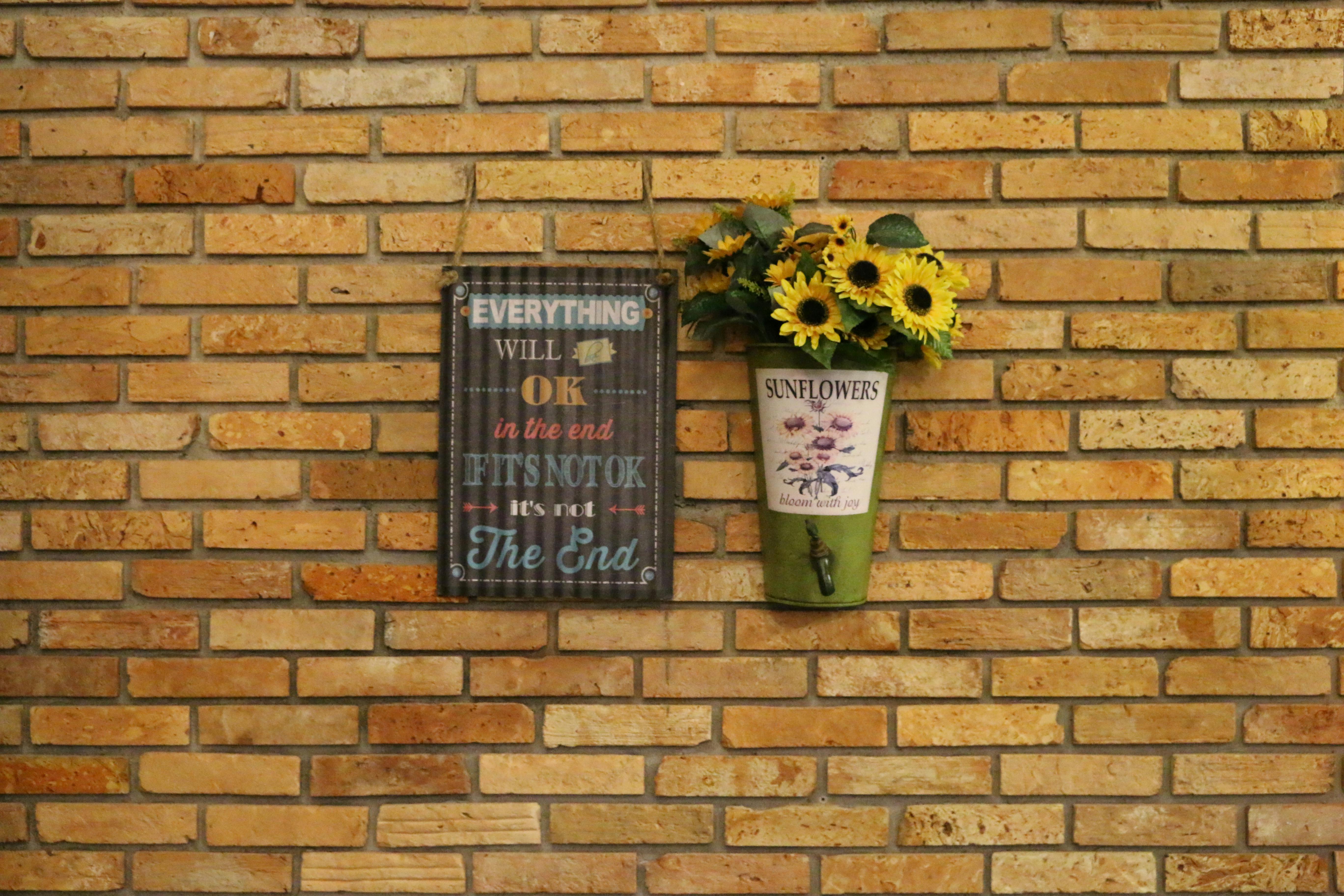 無料 インスピレーションを与える看板とひまわりの装飾が施されたレンガの壁。 写真素材