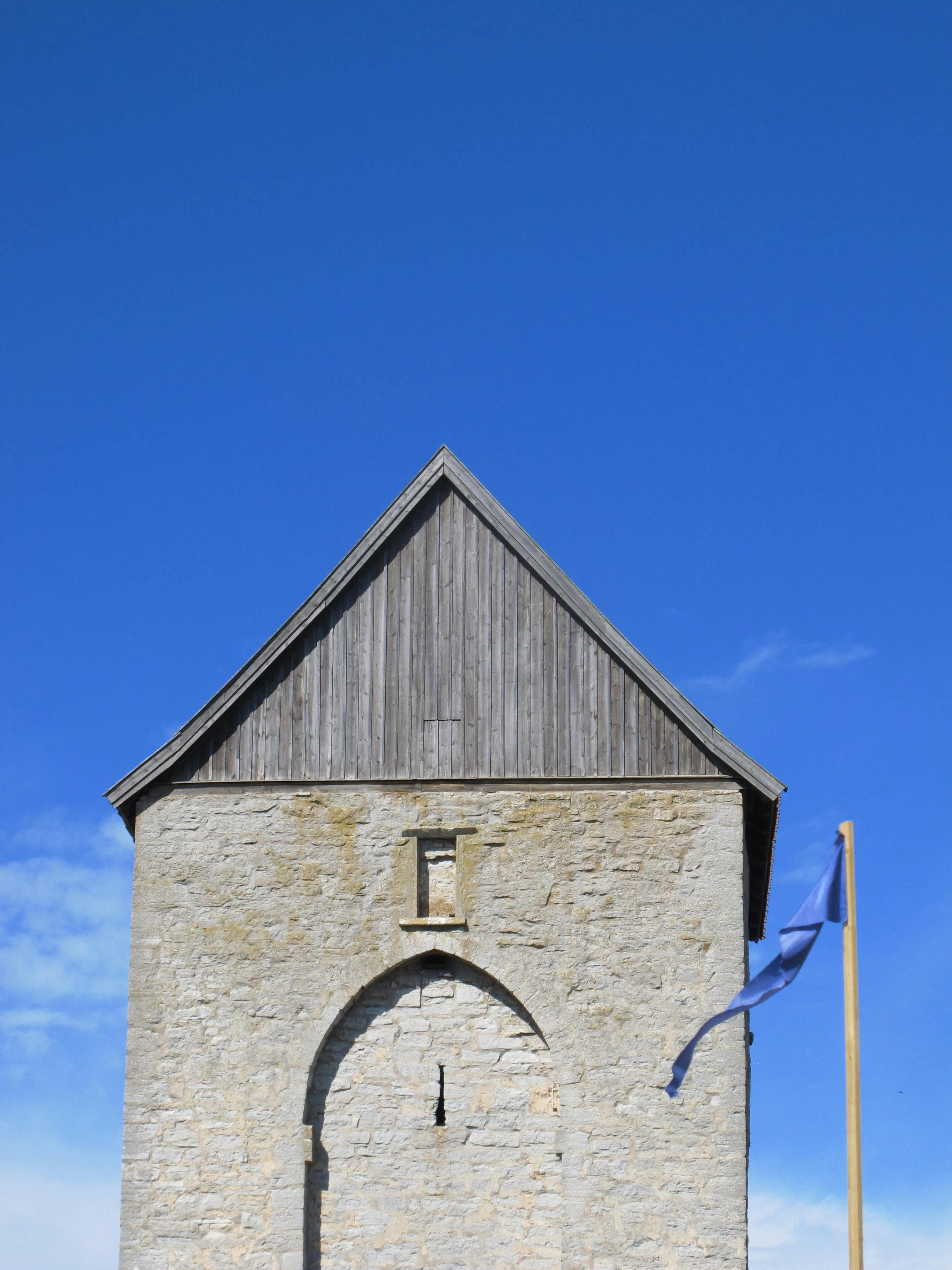 無料 澄み切った青空の下にあるスウェーデンのヴィスビーにある歴史的な中世の塔は、北欧建築の典型です。 写真素材