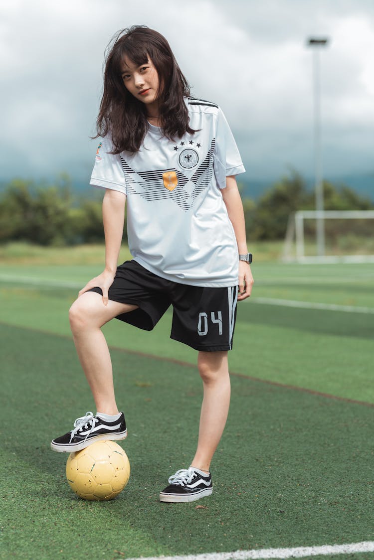 Woman Wearing White Soccer Jersey Shirt And Black Shorts While Standing On Soccer Field