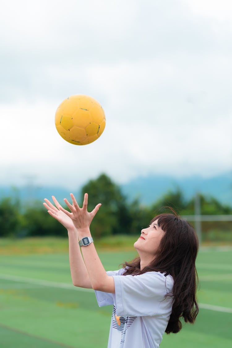 Woman Wearing White T-shirt While Catching A Soccer Ball