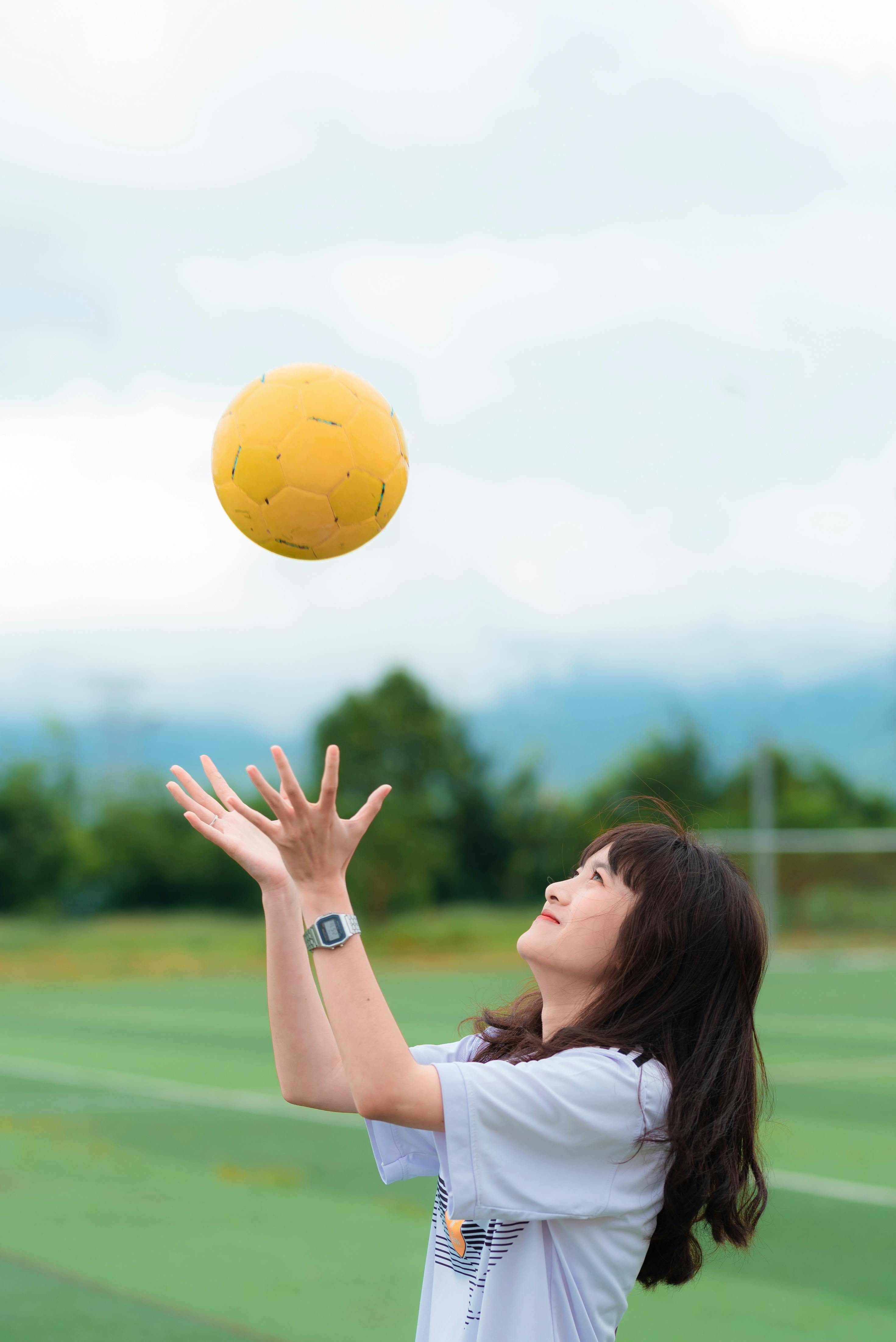 Mujer Vistiendo Camiseta Blanca Mientras Atrapa Un Balón De Fútbol · Fotos de stock gratuitas