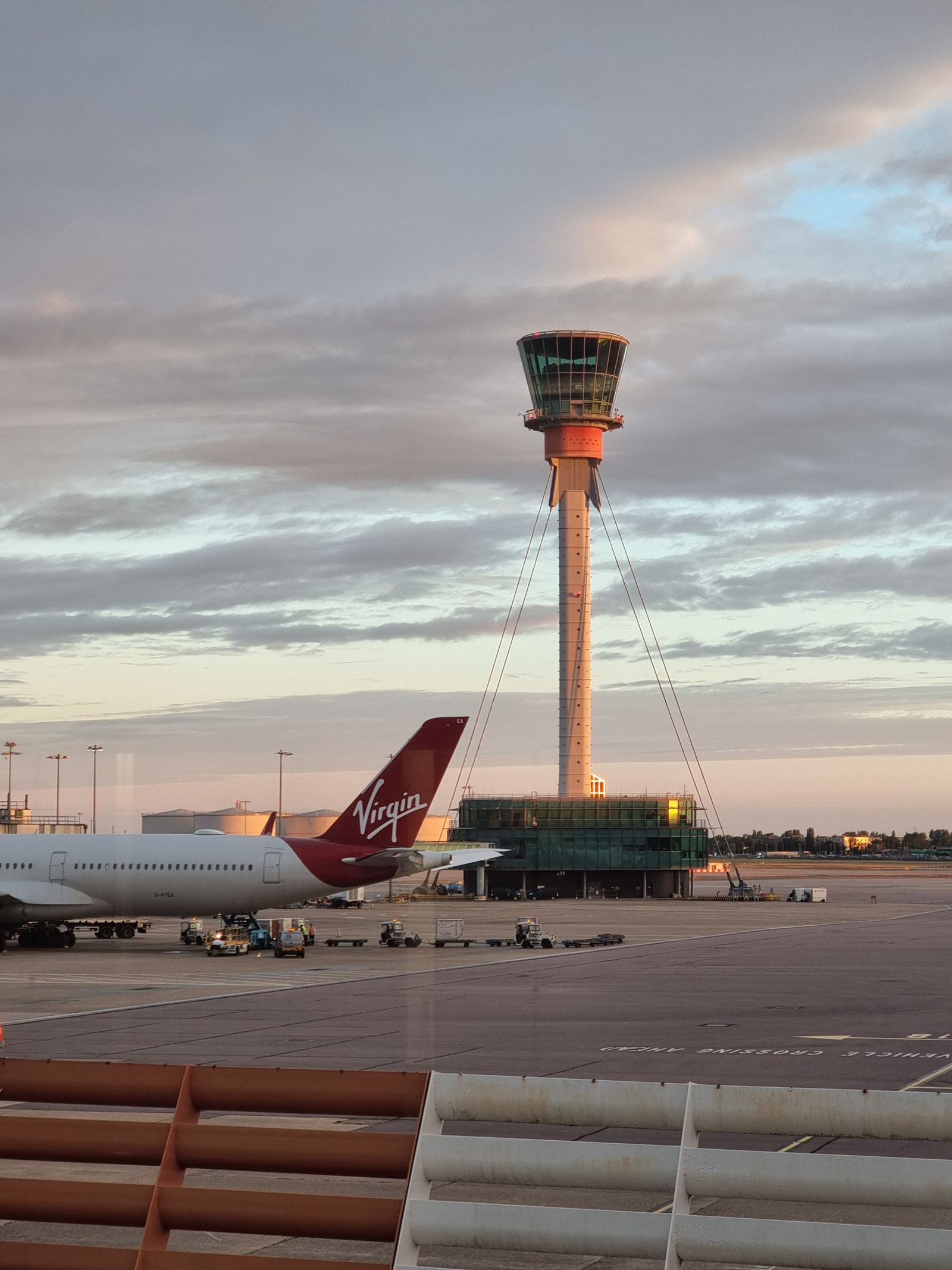 Wide terminal concourse at a major London airport with travelers walking toward gates