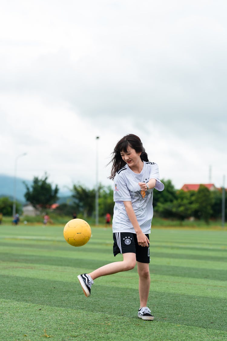 Woman In White Shirt And Black Shorts Playing Soccer