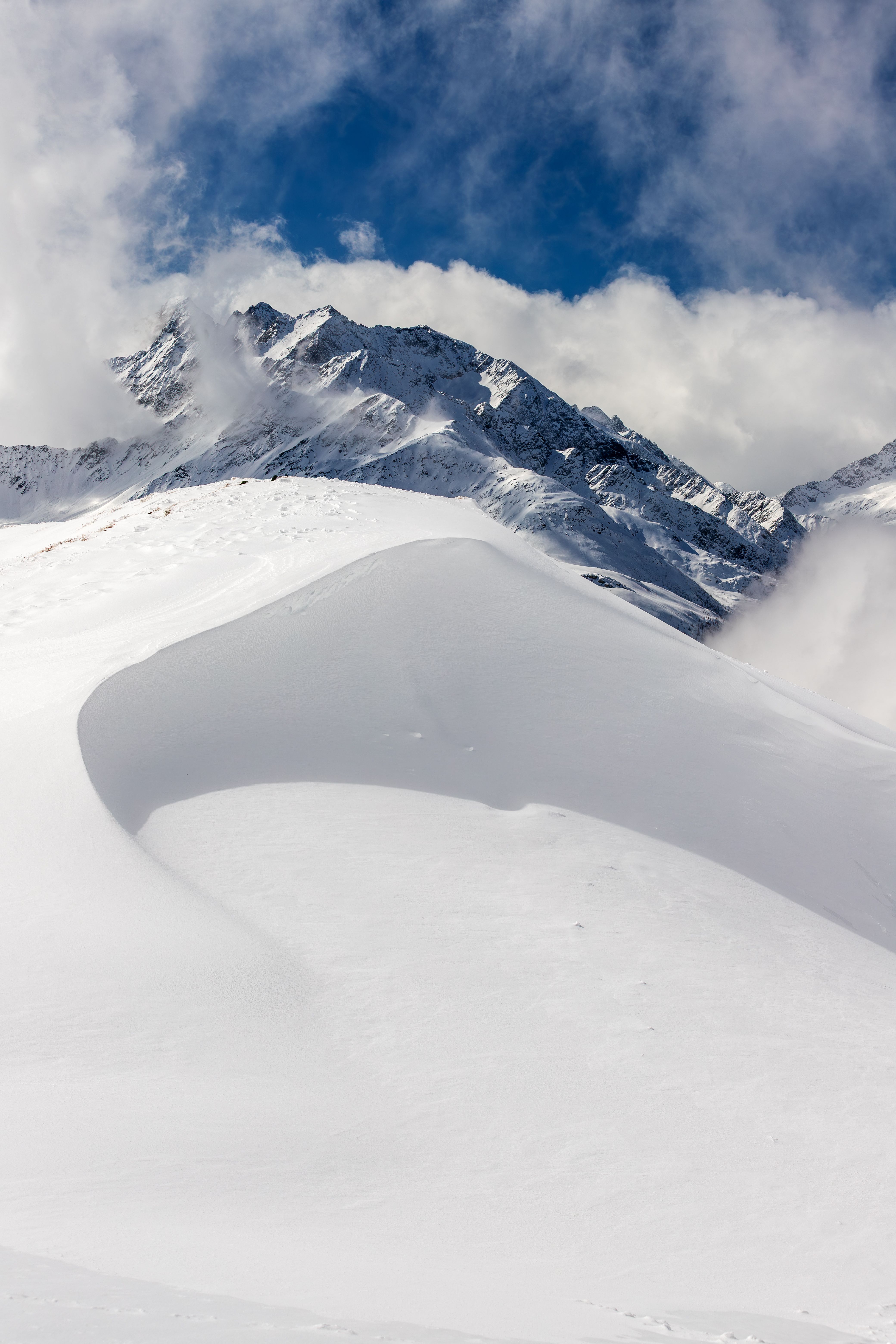 Dramatic snow-covered mountains and rugged peaks under a vibrant sky in Korutany, Rakousko.