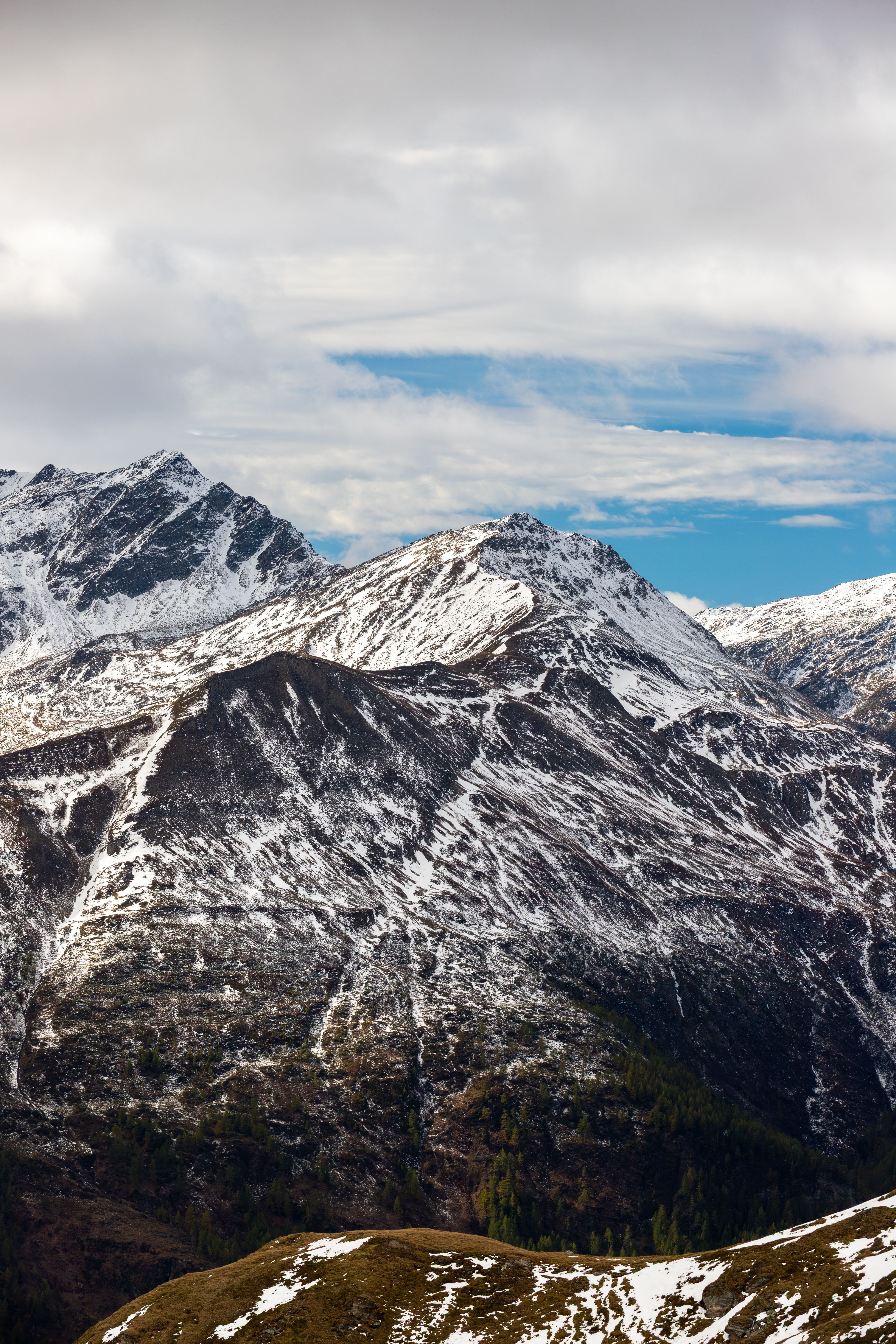 Explore the stunning snow-capped mountains of Korutany with dramatic skies and rugged terrain.