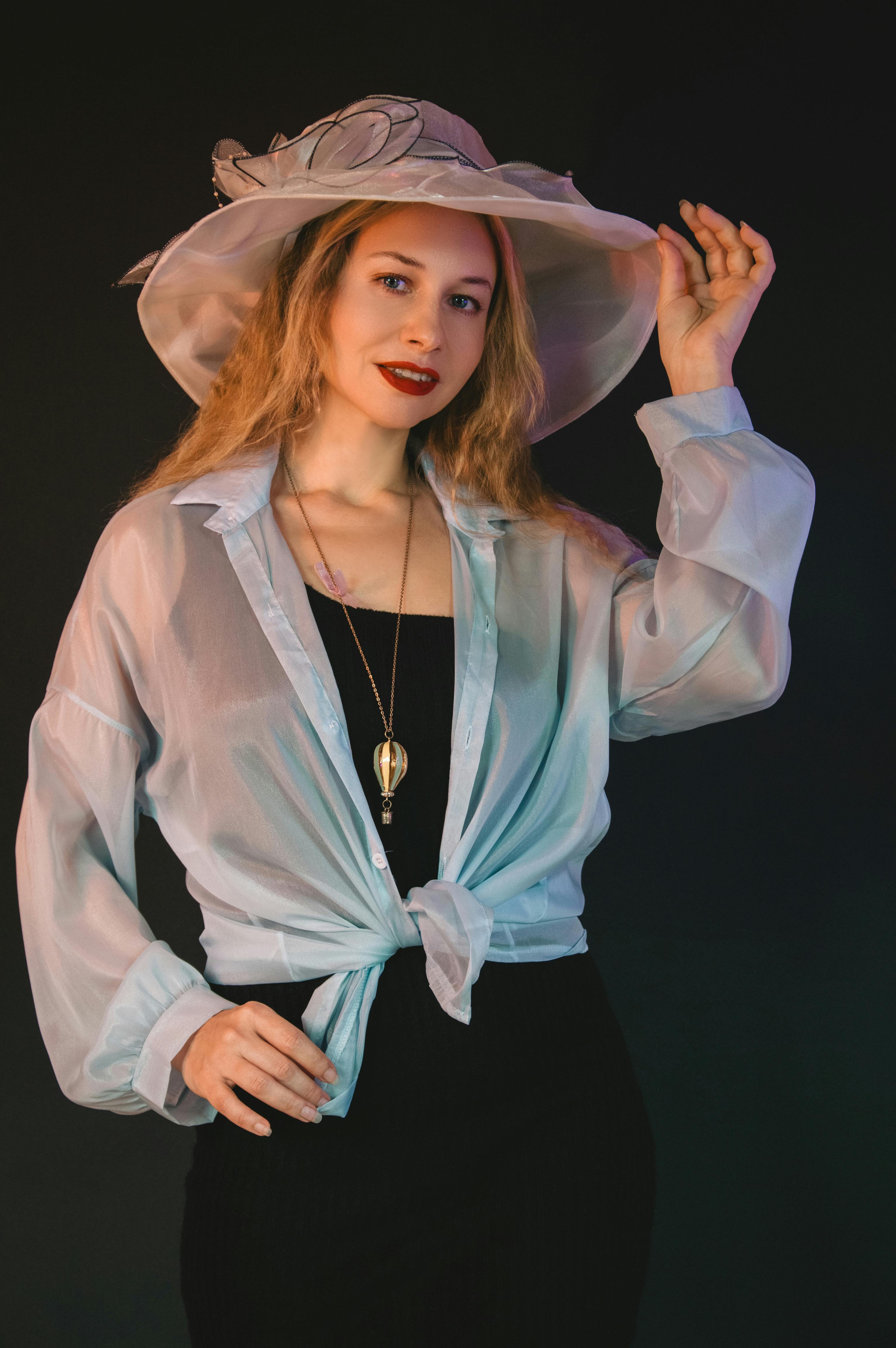 Gratis Elegante ritratto di una donna con cappello e camicetta alla moda, in posa sicura di sé. Foto a disposizione