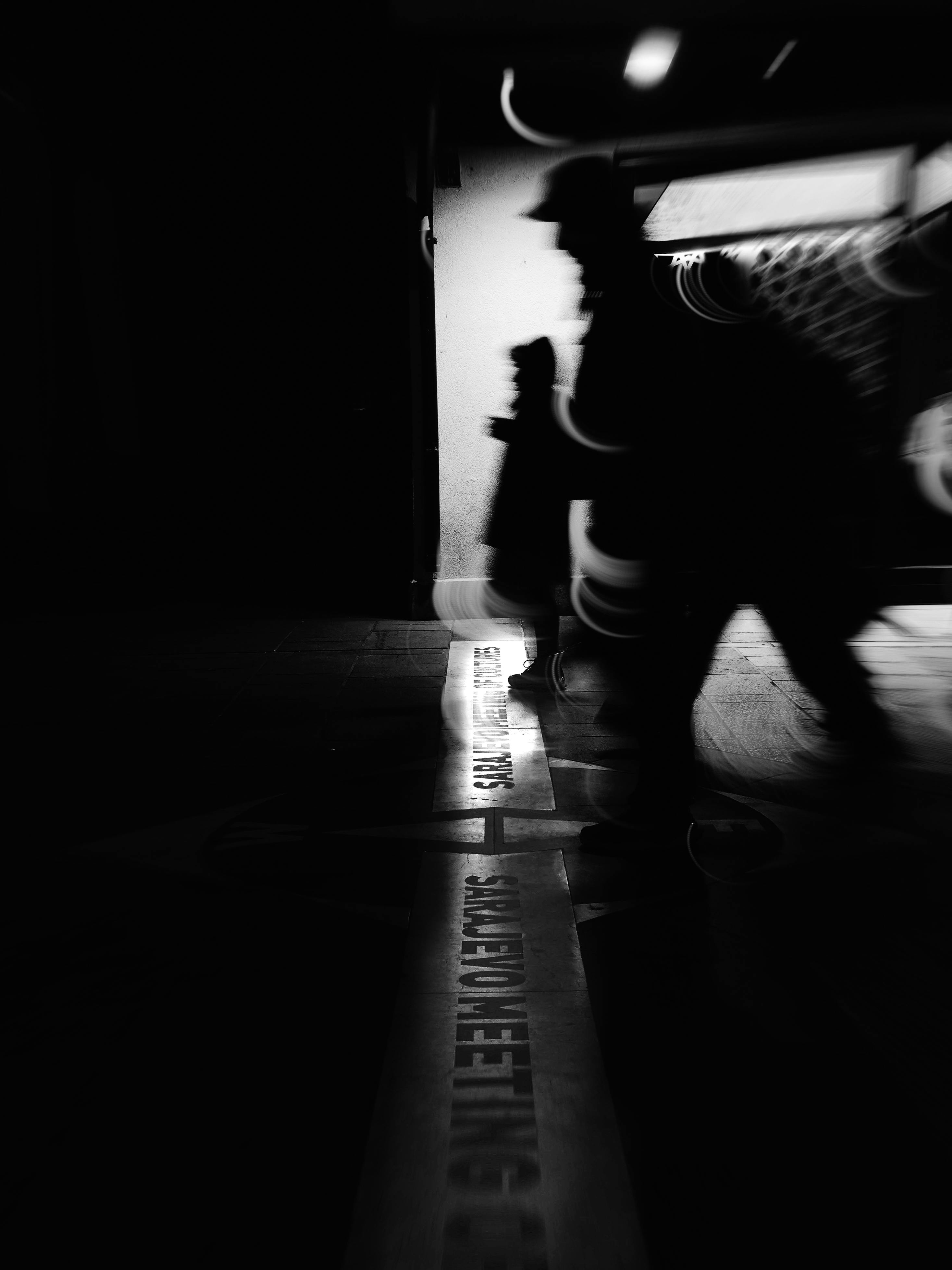 Gratis Figure ombrose si muovono nel paesaggio urbano cupo di Sarajevo, creando una scena cittadina enigmatica. Foto a disposizione