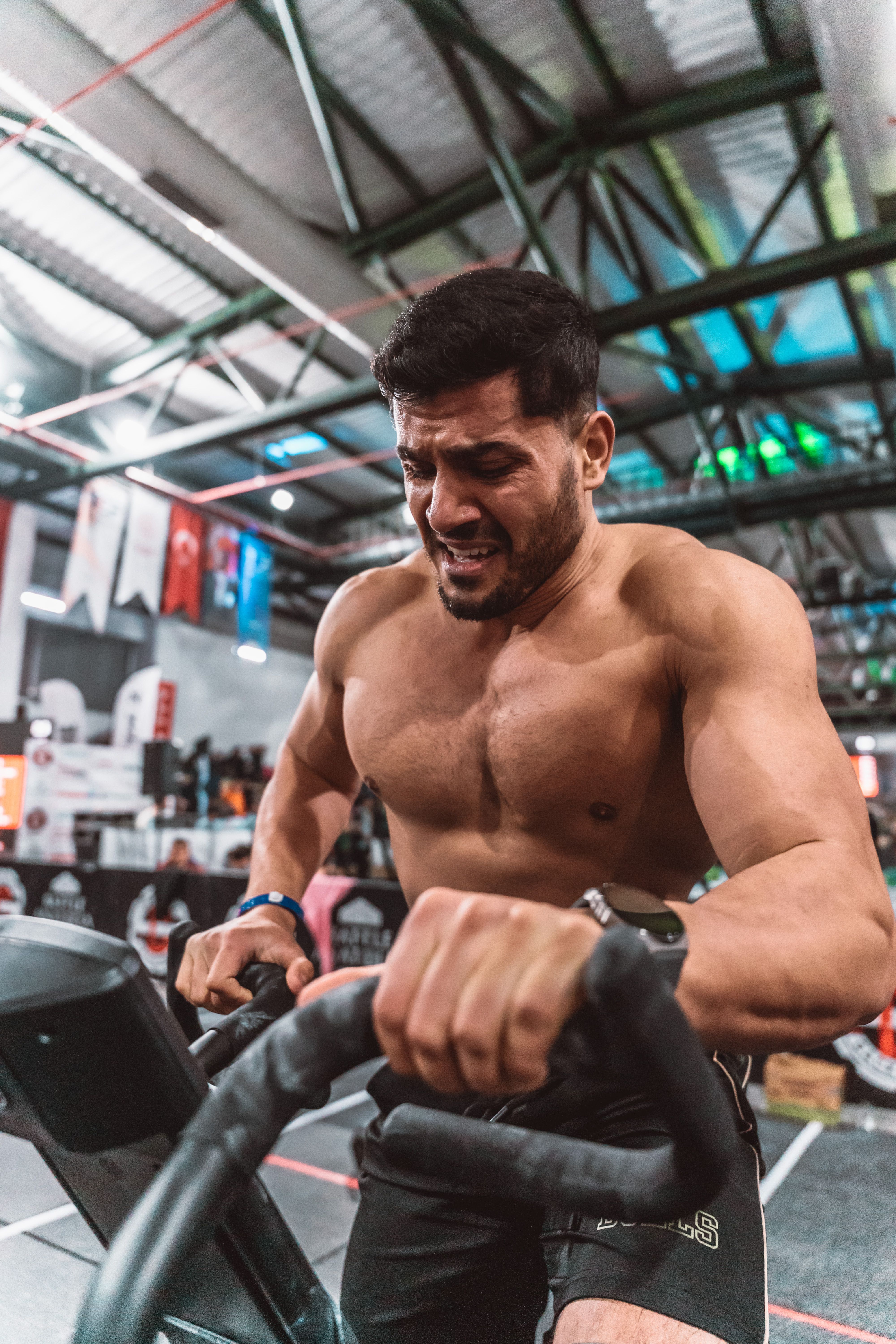 A determined man exercising on a stationary bike in a gym setting.