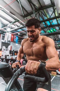 A determined man exercising on a stationary bike in a gym setting.