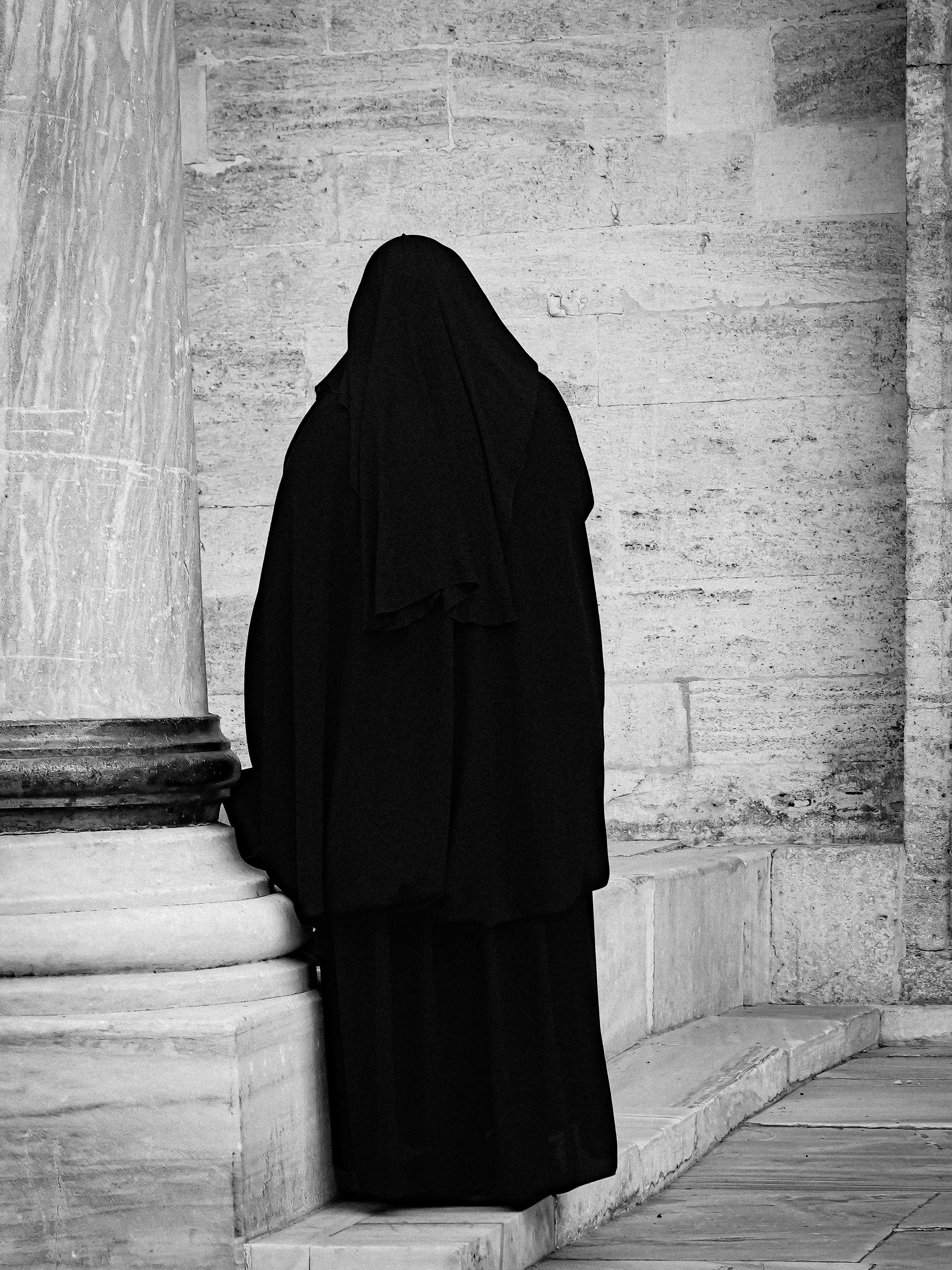 Gratuit Imagine alb-negru a unei persoane într-o pelerină stând lângă coloana istorică de piatră a Istanbulului. Fotografie de stoc