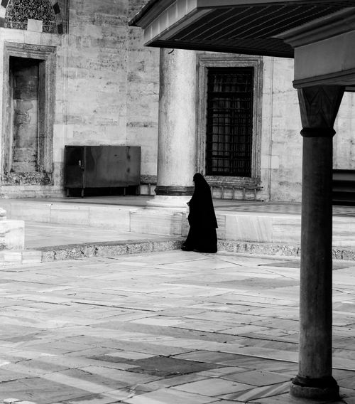 Free A solitary figure in black robes walks through a historic mosque courtyard in Istanbul, Türkiye. Stock Photo