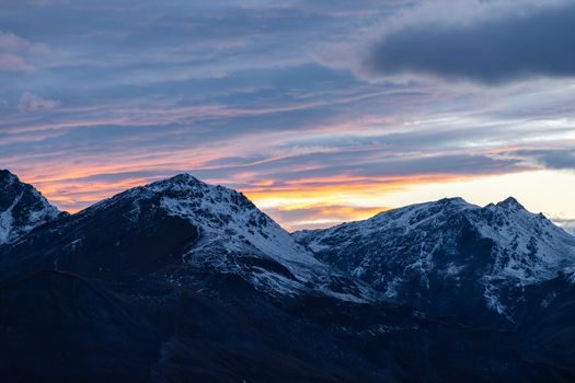 Breathtaking sunset over snow-capped mountains in Korutany, Rakousko with a vivid sky.