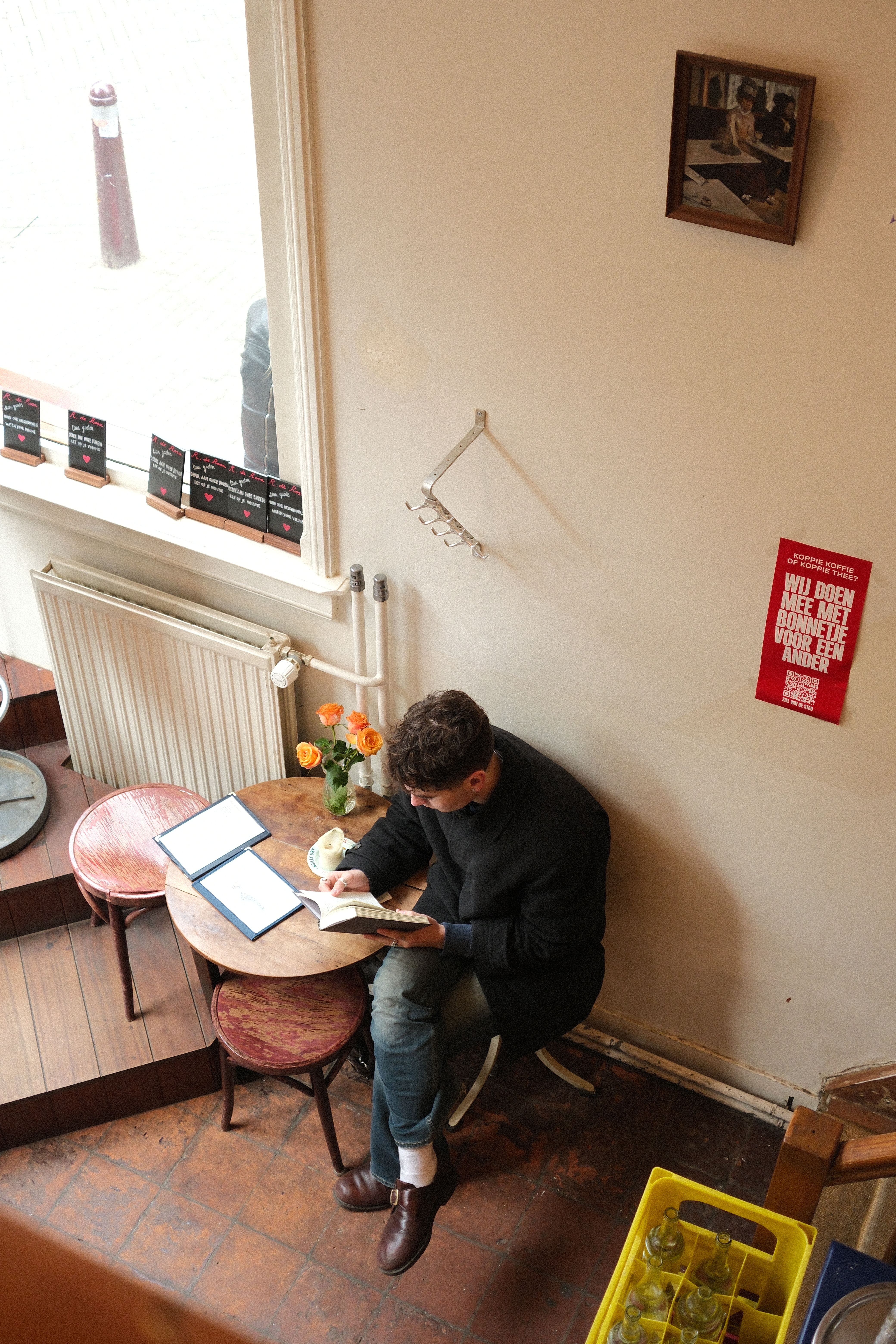 A man enjoys a quiet reading moment in a cozy café in Amsterdam.