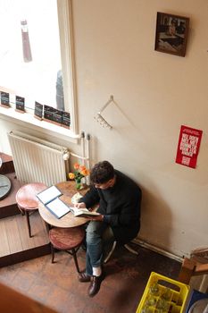 A man enjoys a quiet reading moment in a cozy café in Amsterdam.