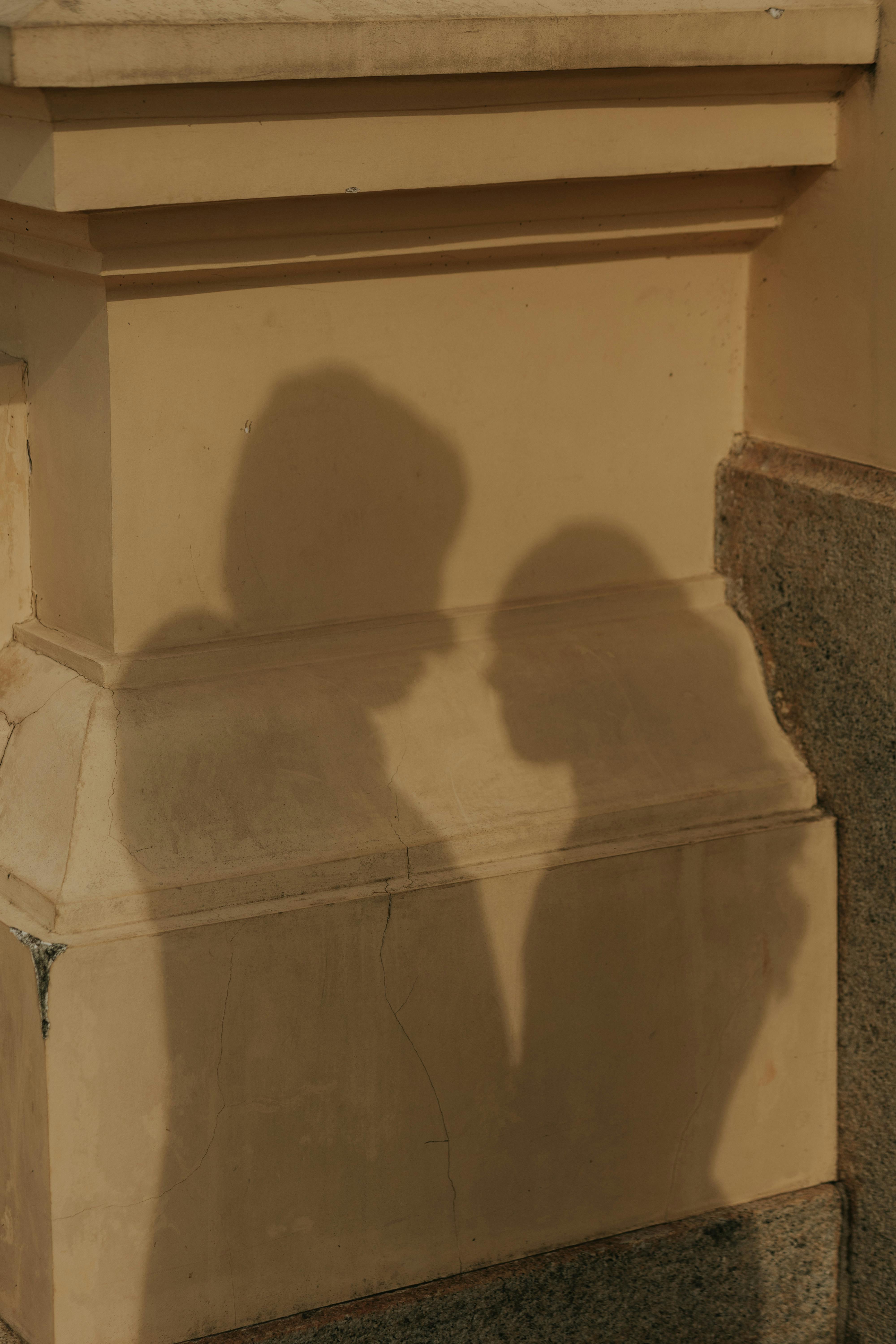 De franc Ombres artístiques de dues persones en una paret urbana, creant una atmosfera misteriosa i romàntica. Foto d'estoc