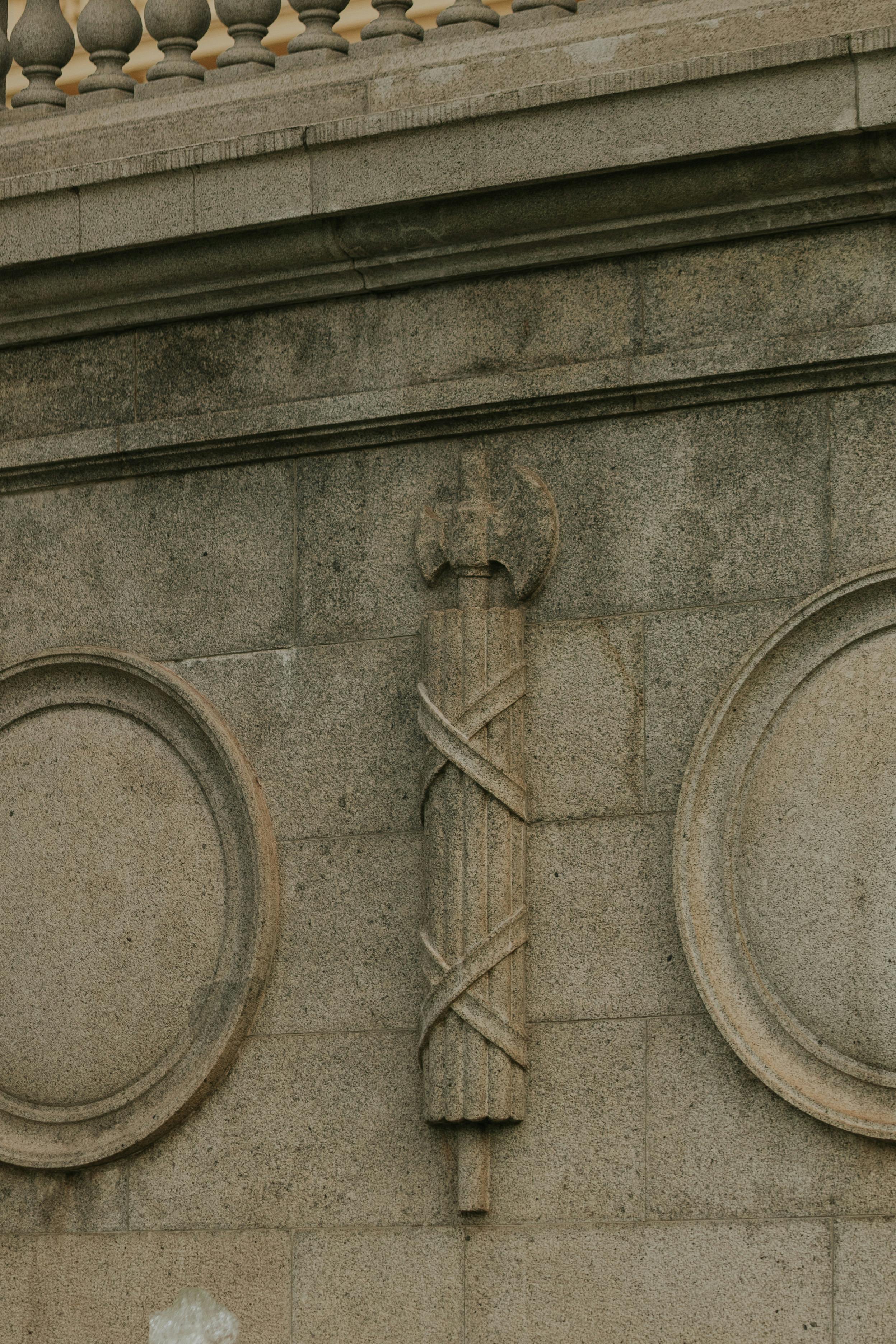 Gratis Primo piano di un bassorilievo in pietra raffigurante un emblema storico sulla facciata di un edificio. Foto a disposizione