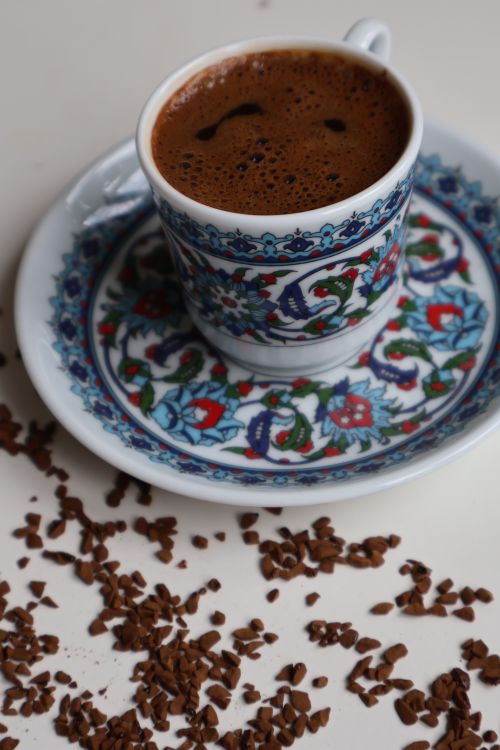 Free An ornate Turkish coffee cup surrounded by ground coffee on a white surface. Stock Photo