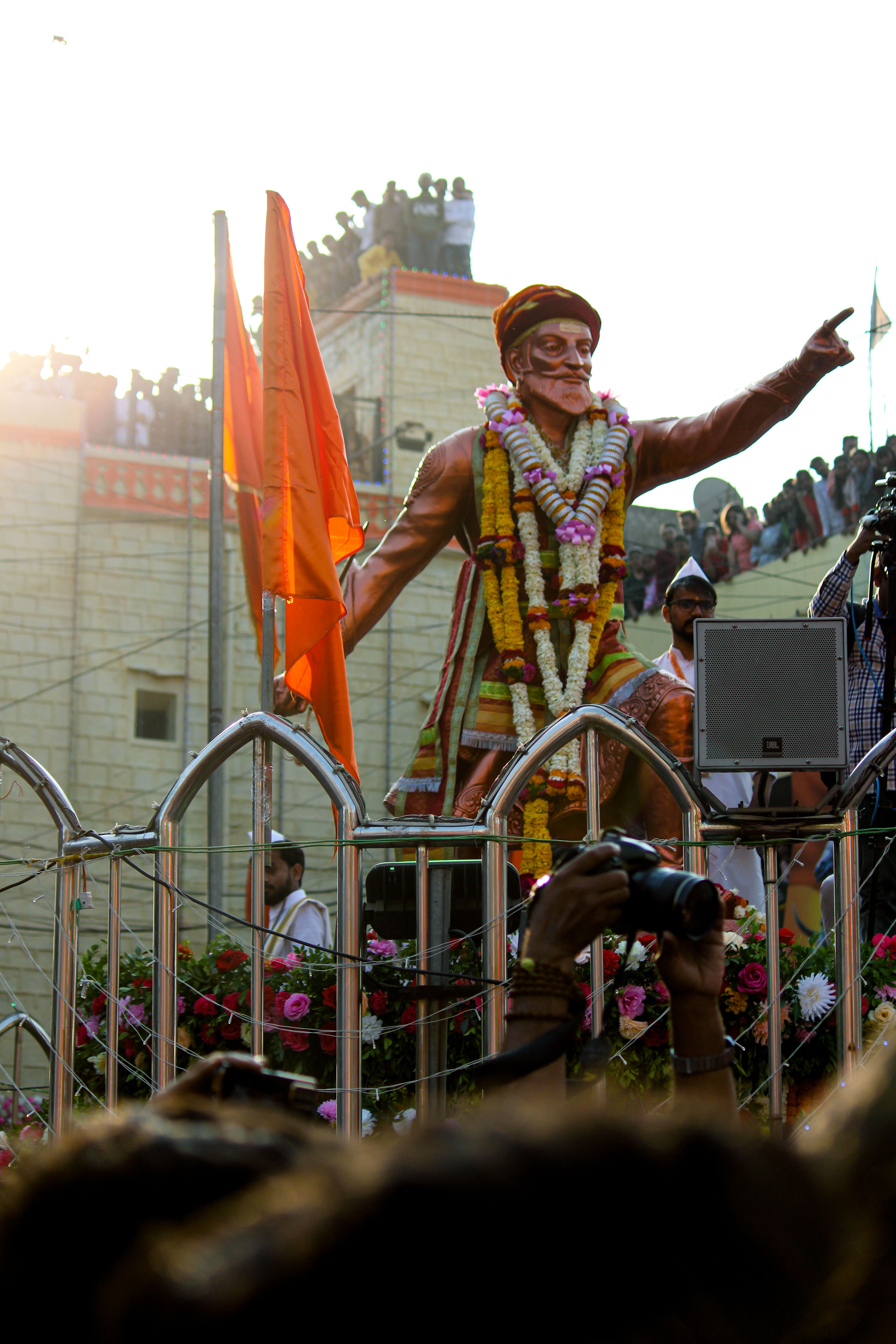 Statue of Chhatrapati Shivaji adorned with garlands and saffron flags at a celebration in Nagpur, India.