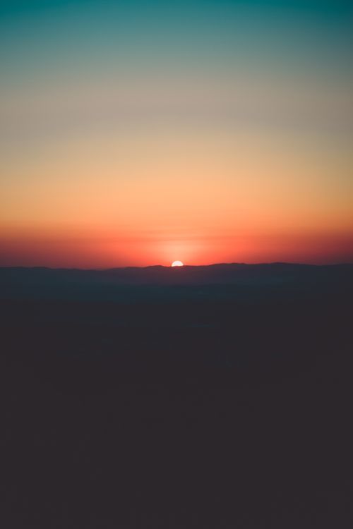 Free Beautiful sunset with vibrant colors and mountain silhouettes. Stock Photo