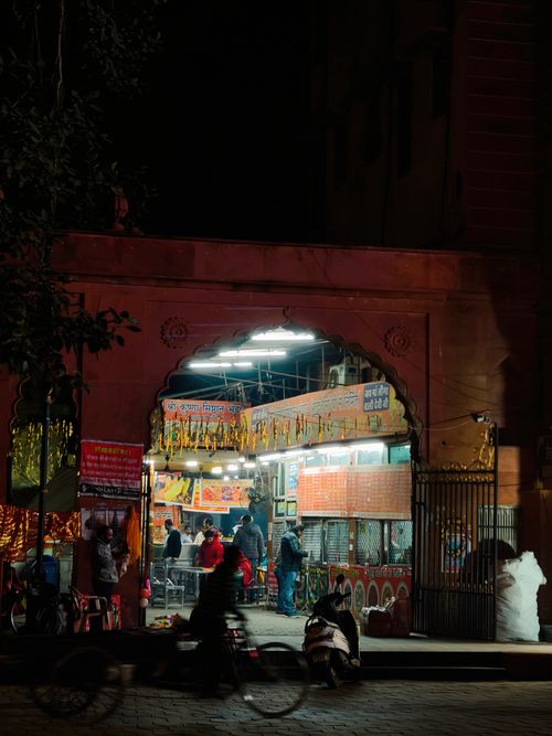 Free A lively night scene at a street food stall in Amritsar, India, illuminated under archway. Stock Photo