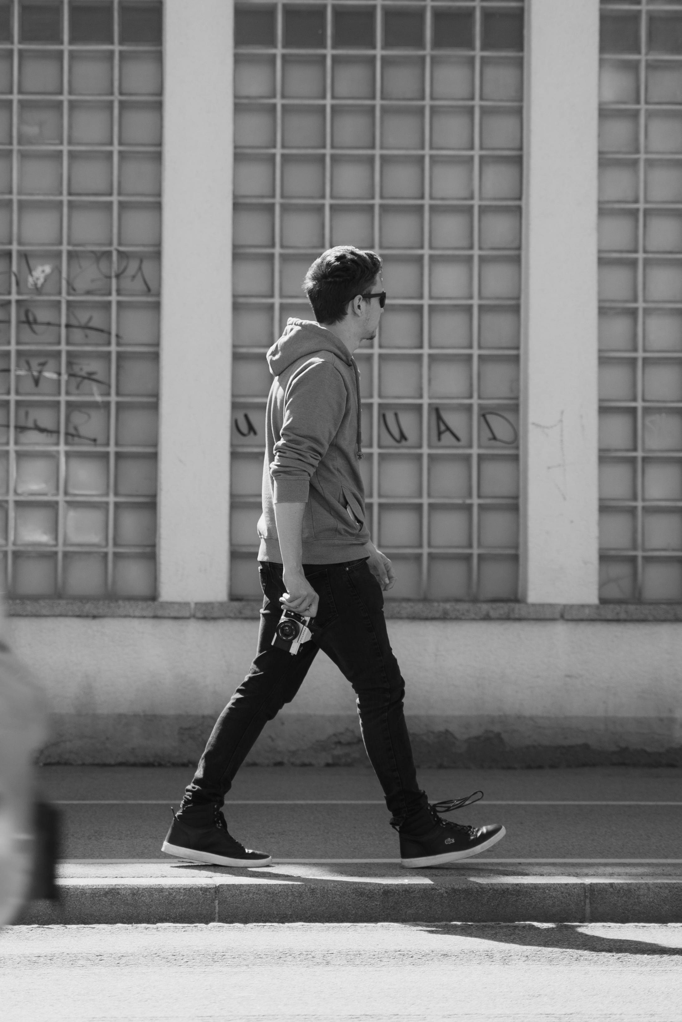 ฟรี ภาพถ่ายขาวดำแสดงให้เห็นชายคนหนึ่งกำลังเดินพร้อมกล้องถ่ายรูป โดยมีฉากหลังเป็นหน้าต่าง ในเมืองกราซ ประเทศออสเตรีย คลังภาพถ่าย