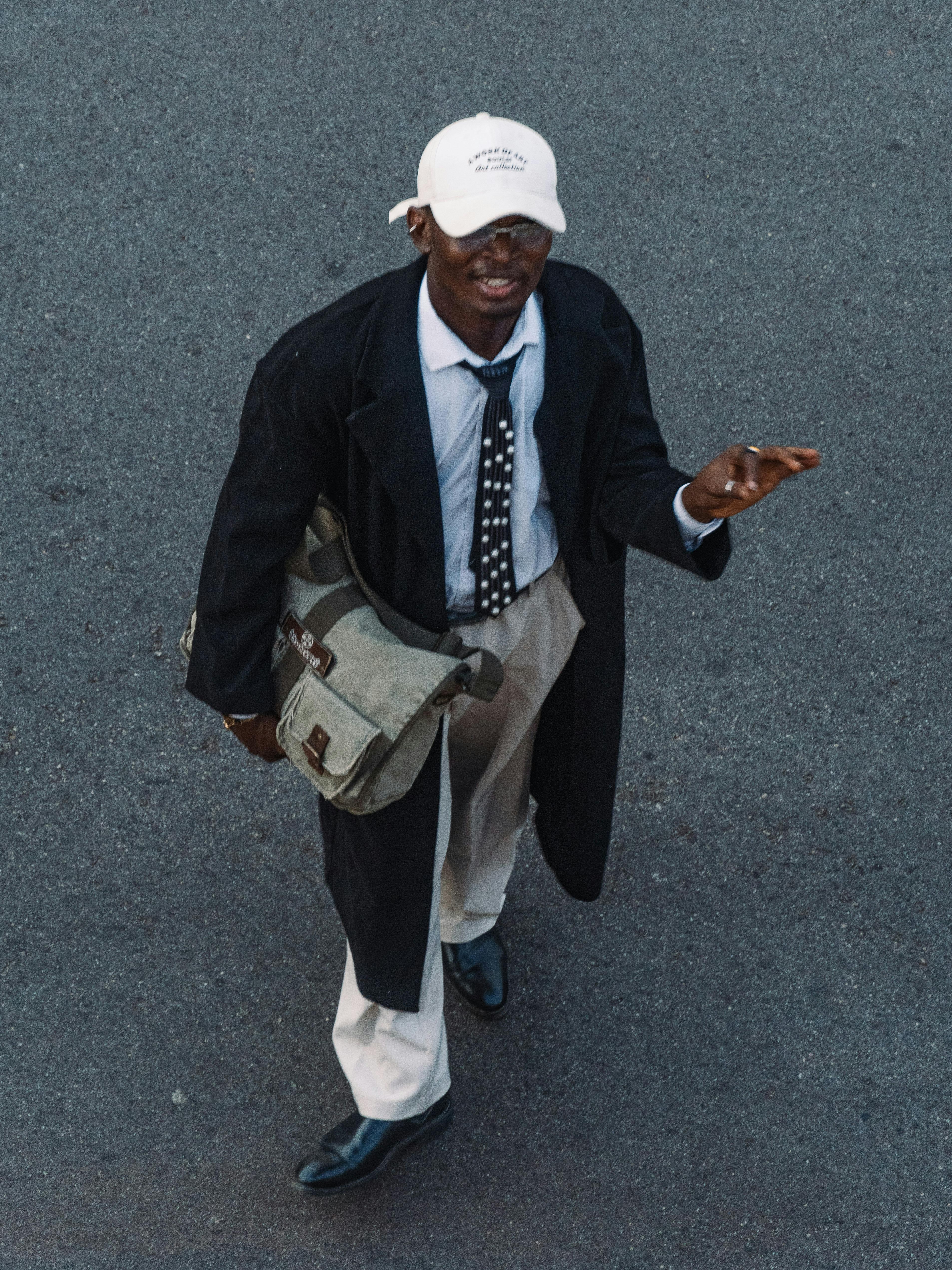 ฟรี ชายหนุ่มทันสมัยคนหนึ่งเดินอยู่บนถนนในเมืองอาบูจา แสดงให้เห็นถึงสไตล์และวัฒนธรรมเมือง คลังภาพถ่าย