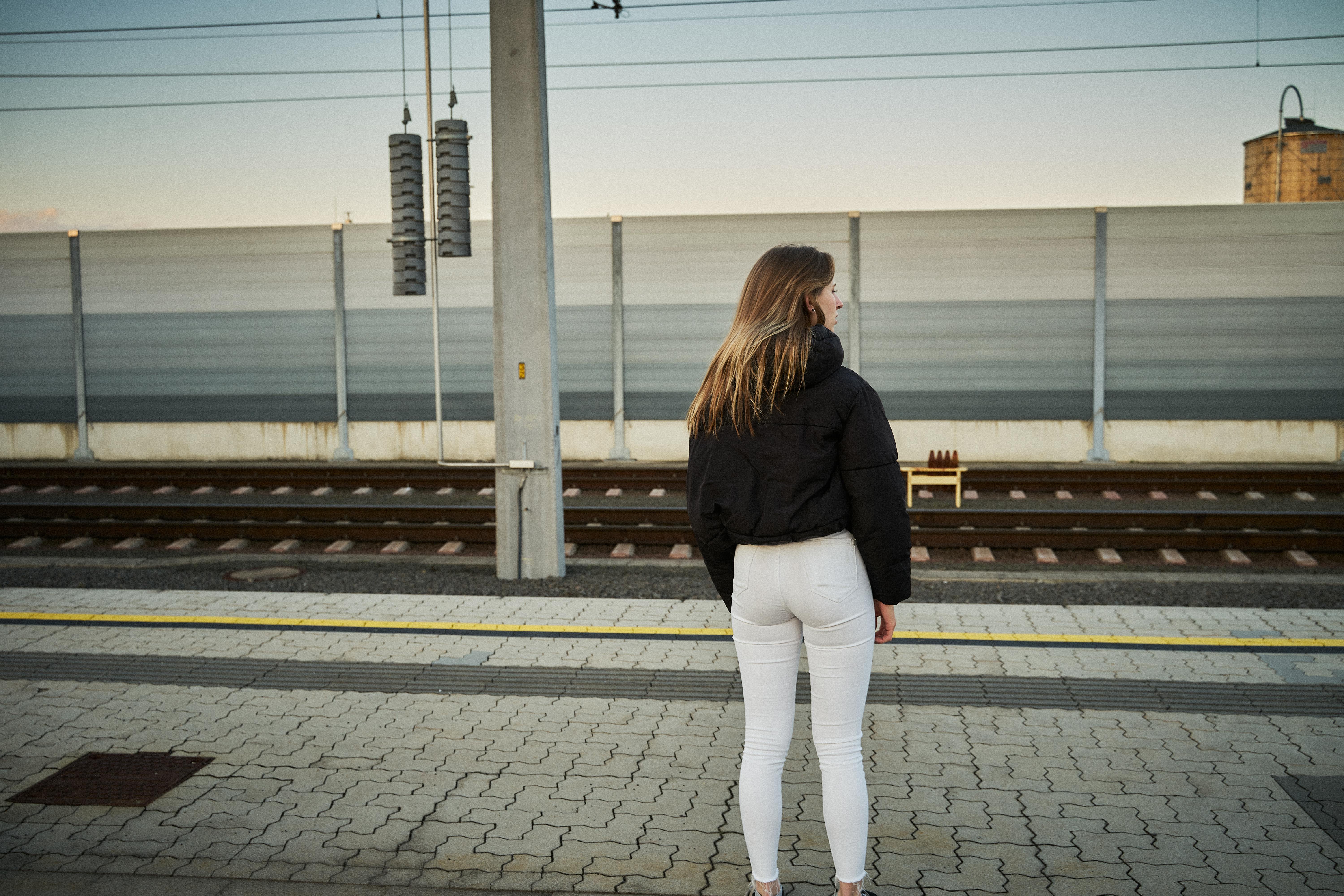 Gratis En kvinde står på Leibnitz togstation, Steiermark, Østrig, og venter på en solskinsdag. Lagerfoto