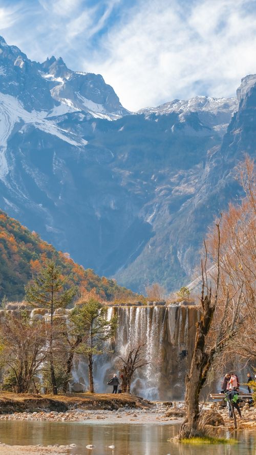 Free Breathtaking view of cascading waterfall against snow-capped mountains in Lijiang during autumn. Stock Photo