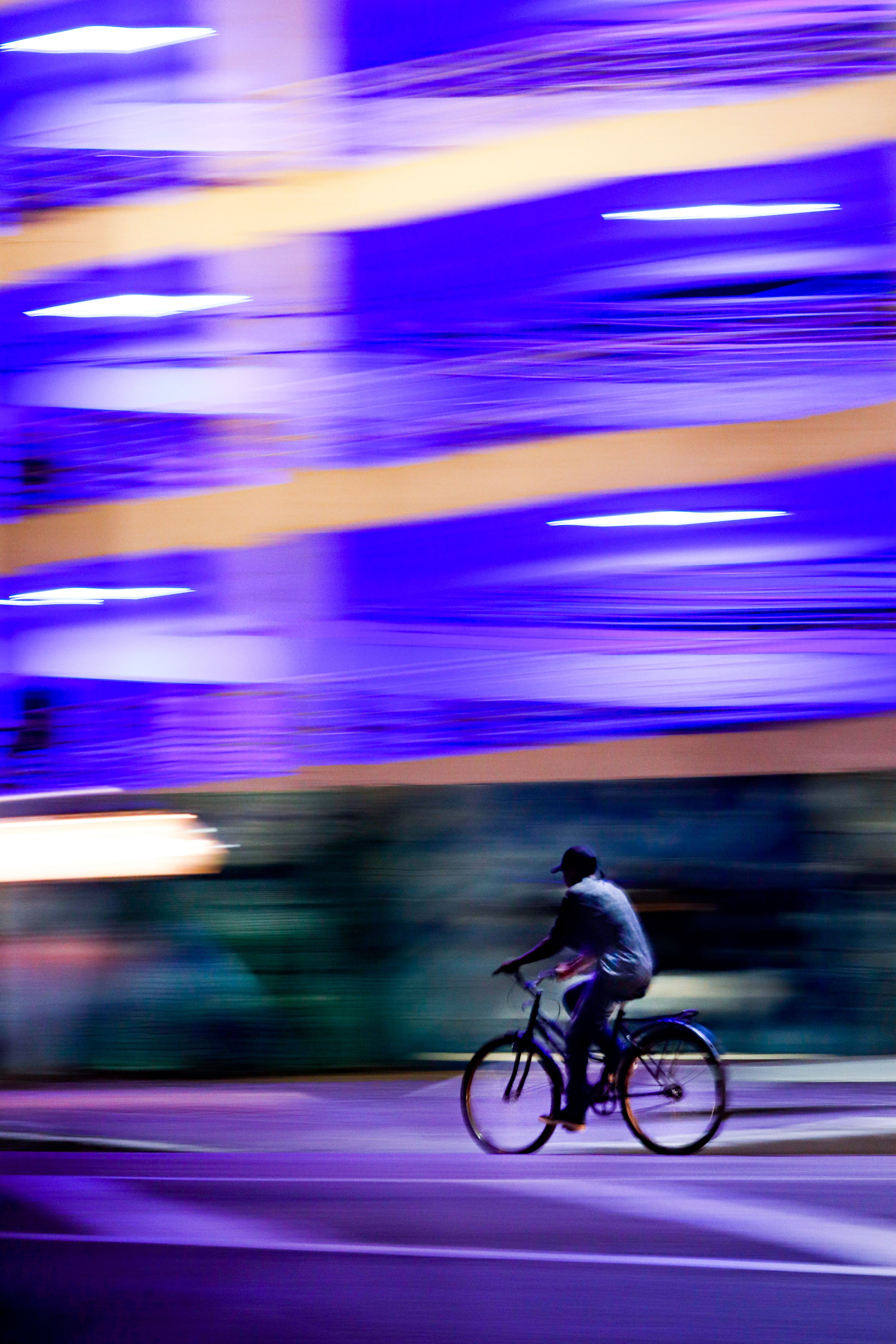 A cyclist rides through vibrant city lights at night in Parintins, Amazonas, Brazil.