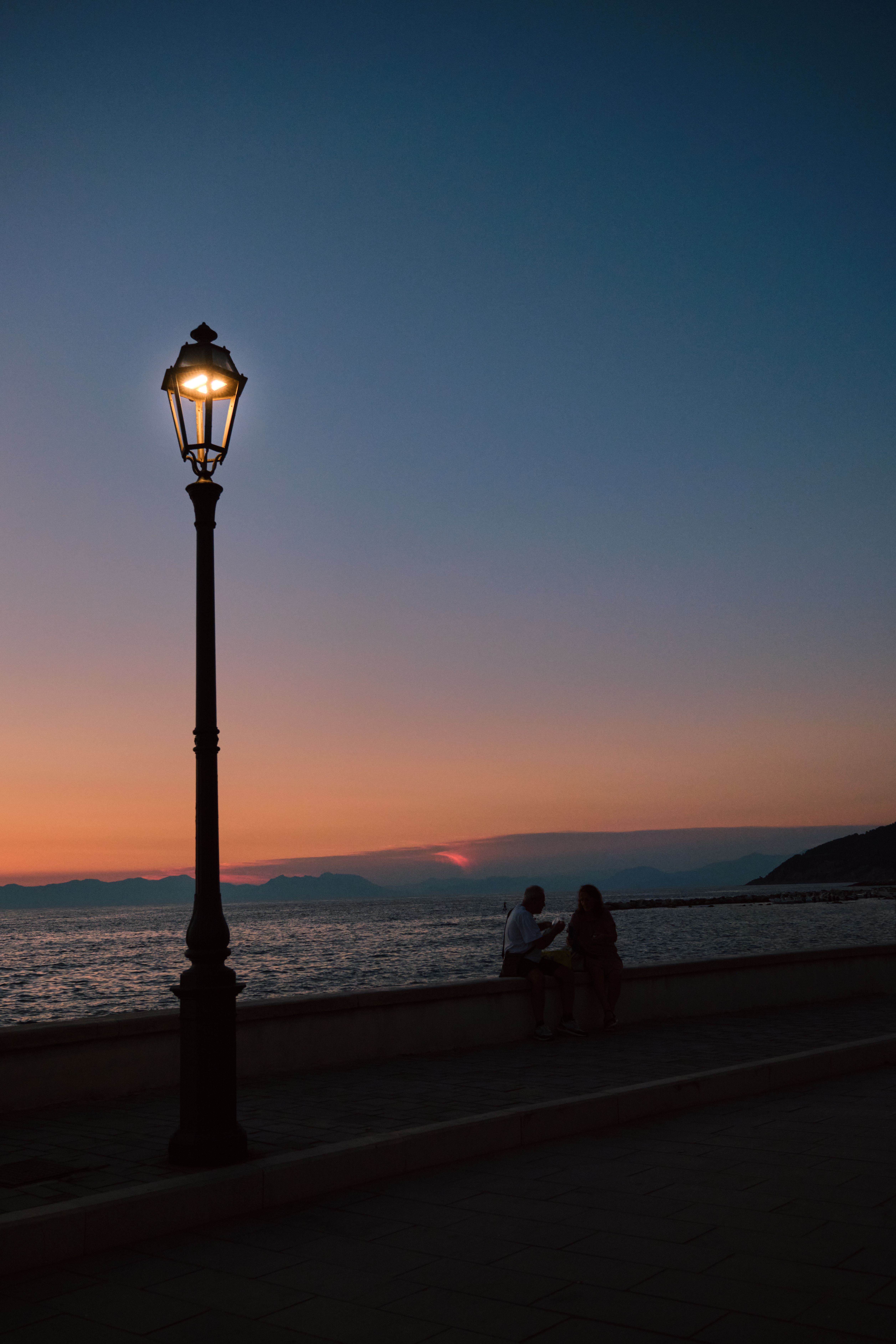 Silhouettes by the sea at sunset in Santa Maria di Castellabate, Campania, Italy.