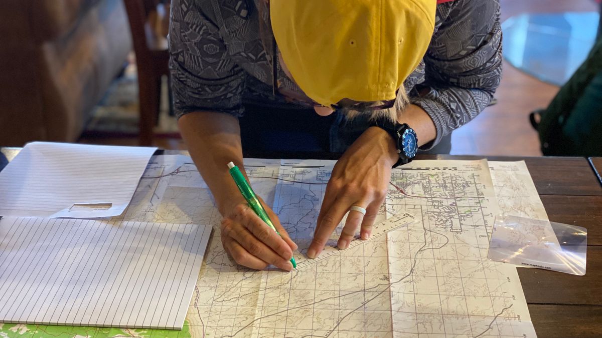 Individual mapping out a route indoors using a map and pen, possibly planning a journey.