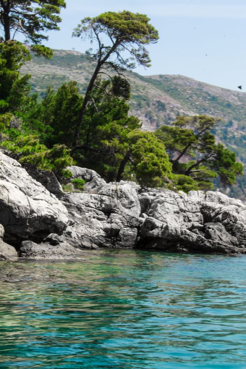 Free Beautiful rocky shoreline along a clear turquoise Mediterranean sea under a sunny sky. Stock Photo