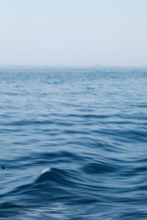 Free Serene ocean scene with gentle waves and a clear blue sky, perfect for relaxation themes. Stock Photo