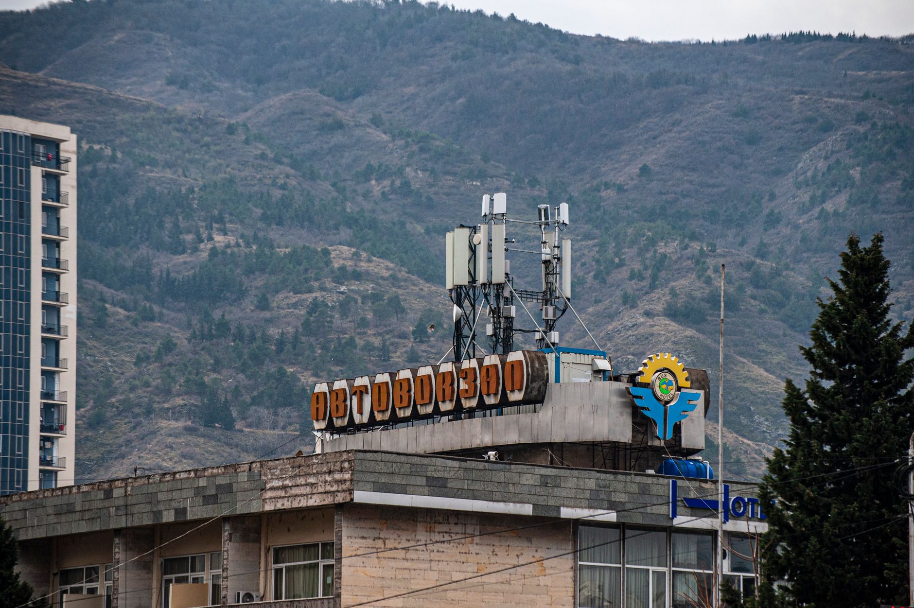 Urban landscape featuring a building with Russian script and mountains in the background, Georgia.
