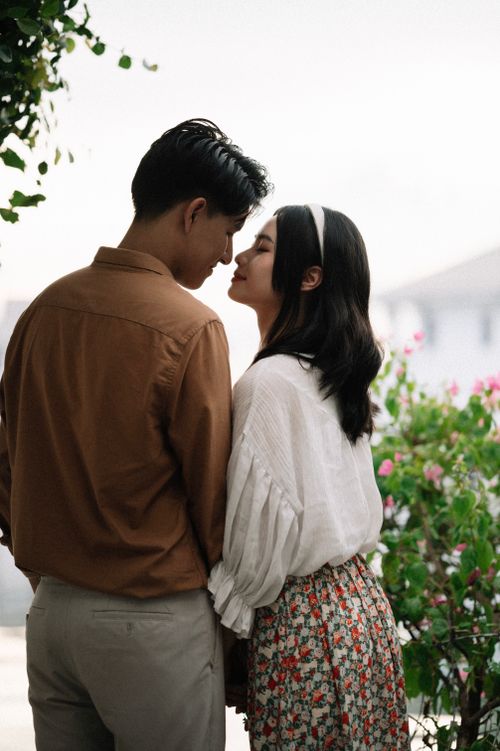 Free A romantic moment between a couple surrounded by blooming flowers outdoors. Stock Photo