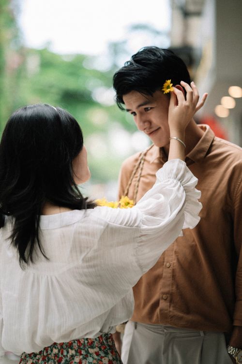 Free Young couple shares a tender moment with flowers in a casual setting. Stock Photo