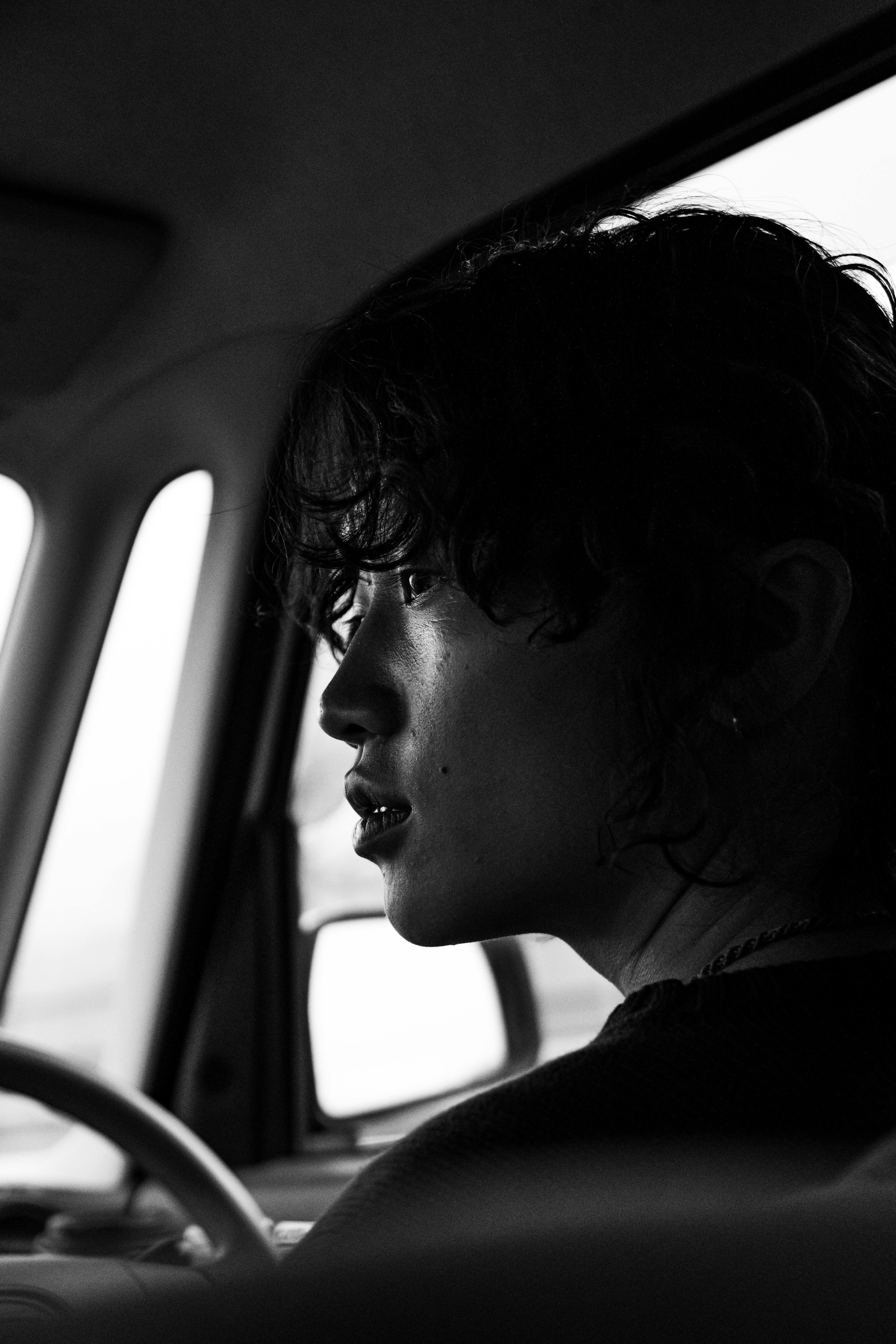 Gratuit Profil d'une personne pensive dans une voiture, capturé dans des tons noir et blanc empreints de mélancolie. Photos