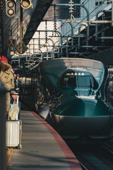 Efficient bullet train at a busy urban station, showcasing modern transportation in Japan.