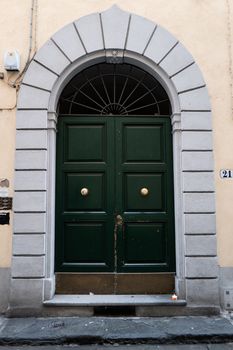 Charming green arched doorway with classic stone frame in Trastevere, Rome.