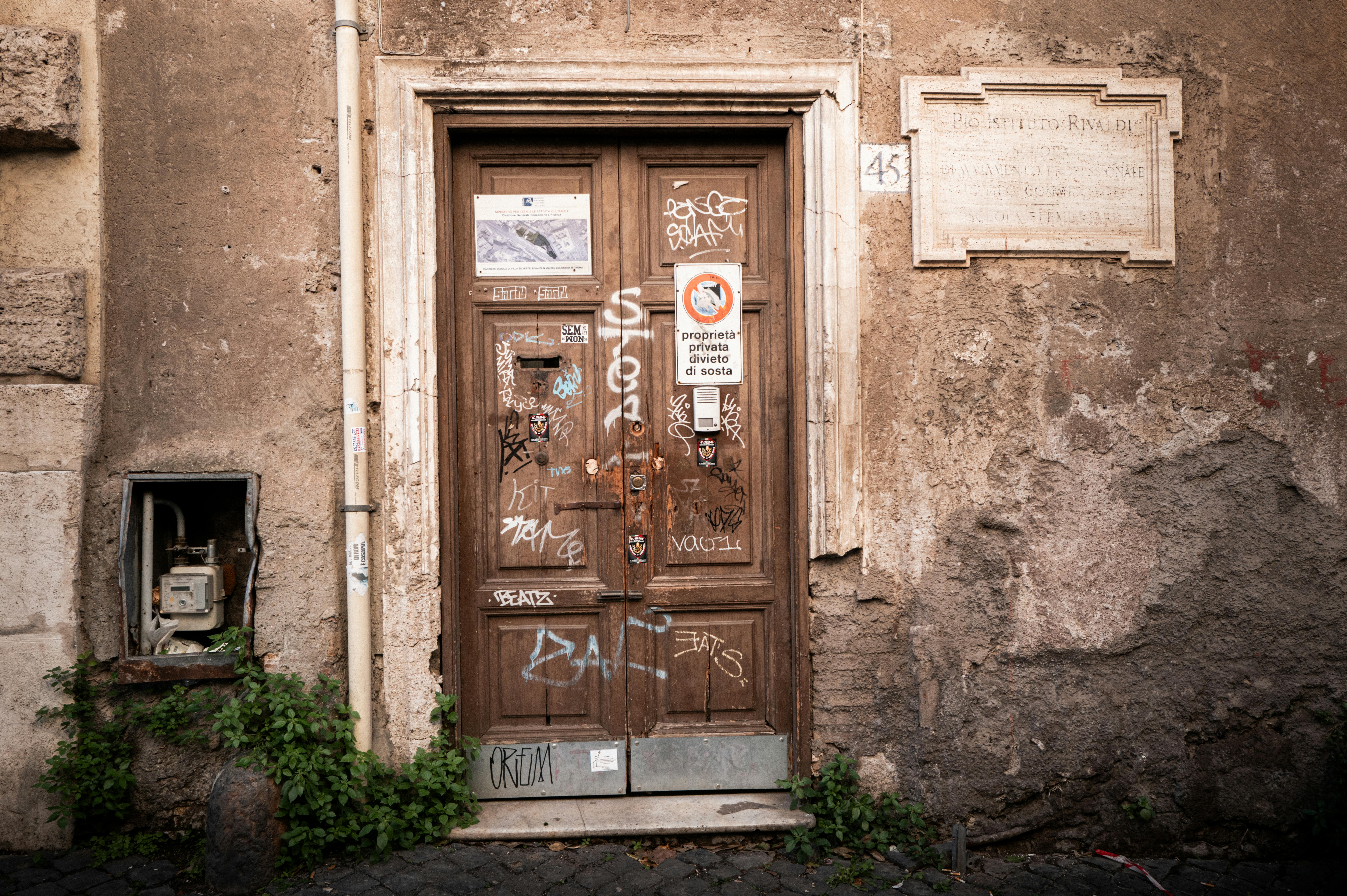 grátis Uma porta de madeira desgastada em Roma, adornada com grafites, captura a essência da arte urbana italiana. Foto profissional
