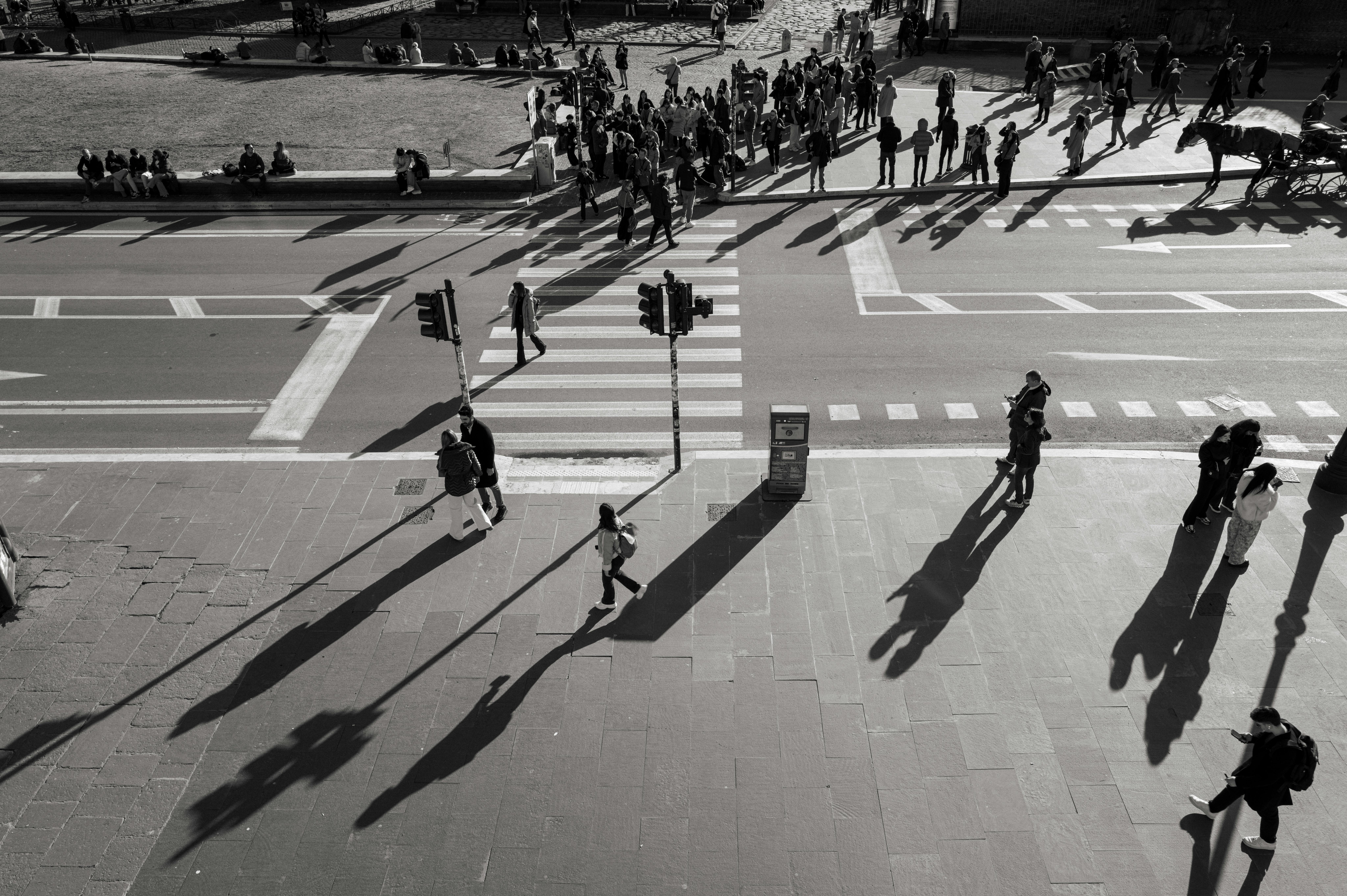 De franc Vista aèria d'un carrer de la ciutat en blanc i negre, que mostra gent i llargues ombres a la posta de sol. Foto d'estoc
