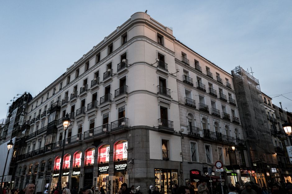 Hermoso edificio histórico iluminado al anochecer en el bullicioso centro de Madrid, que captura la vida urbana y la arquitectura.
